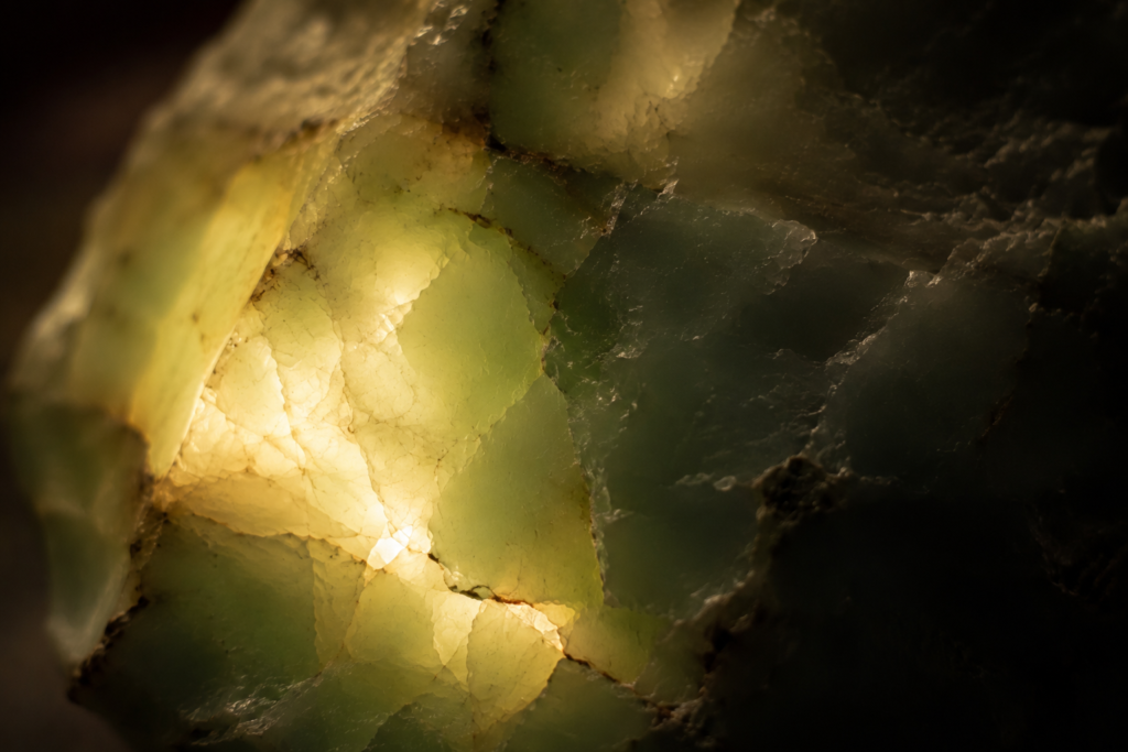 Warm light filtered through natural green jade, highlighting the stone's translucent texture and organic glowing patterns.